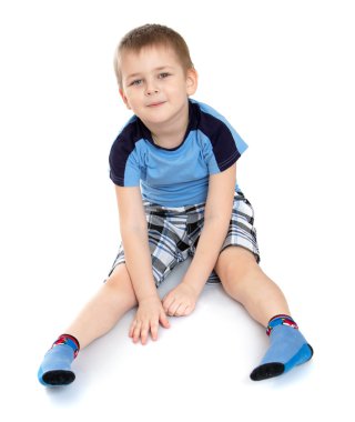 Küçük çocuk yerde oturuyor. 