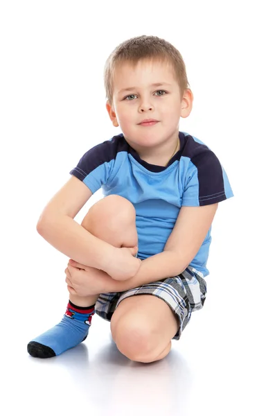 Malý chlapec sedí na podlaze svíral její koleno — Stock fotografie