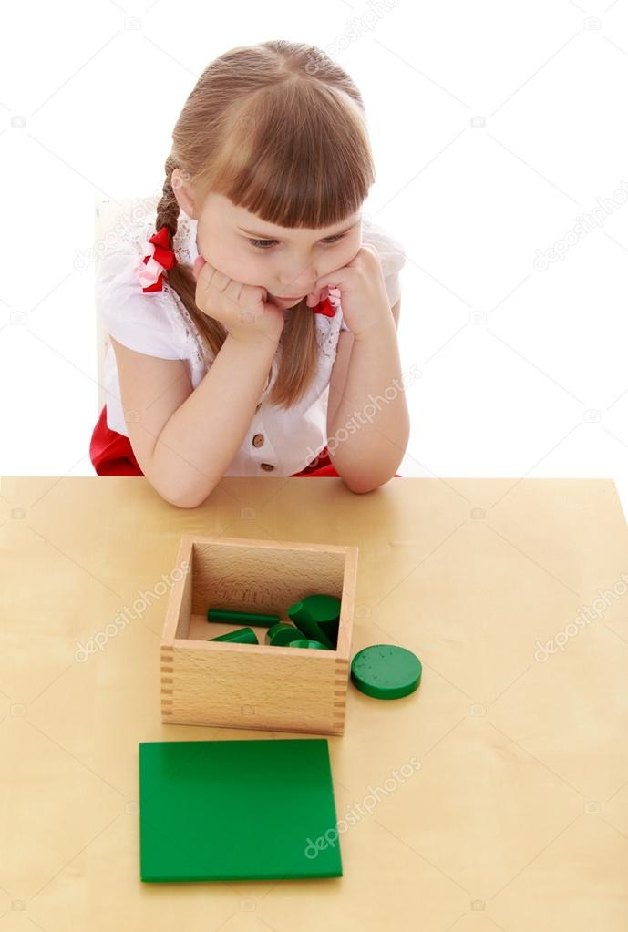 Little girl in a Montessori kindergarten studying the material