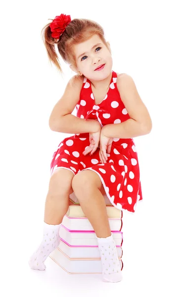 Hermosa niña sentada en una pila de libros — Foto de Stock