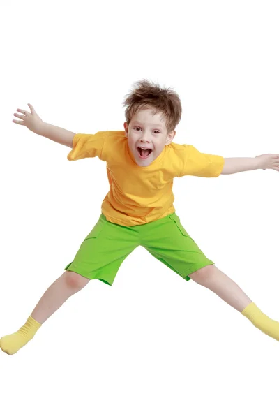 Маленький хлопчик у жовтій футболці та шортах стрибає — стокове фото
