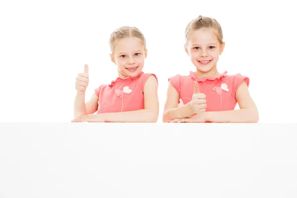 Twin girls look out from behind obstacles — Stok fotoğraf