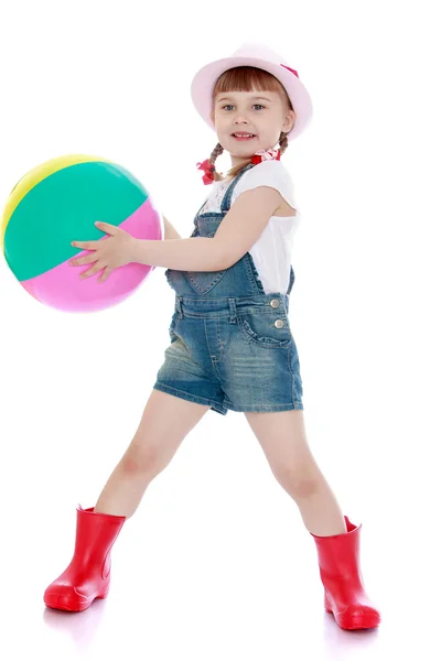 Adorable little girl in denim overalls holding a ball — Stock fotografie