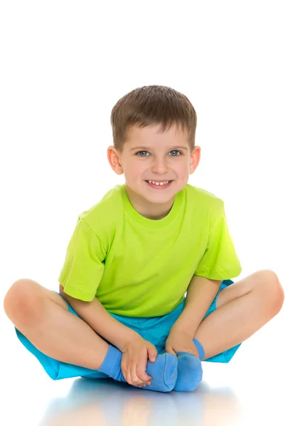 The child sits on the floor with folded legs under him — Stok fotoğraf