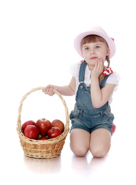 rich harvest of apples lies in the basket which keeps little girl