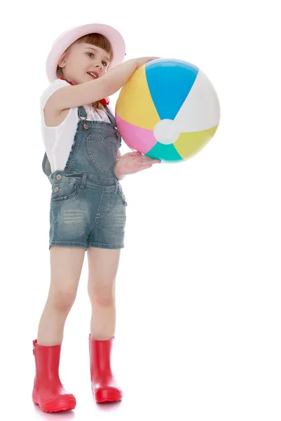 Nice girl in rubber boots and shorts holding a ball — ストック写真