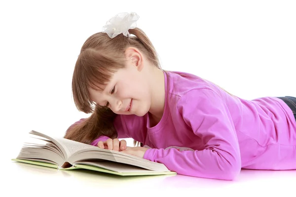 Charmante schoolmeisje lezen van een boek op de vloer liggen — Stockfoto