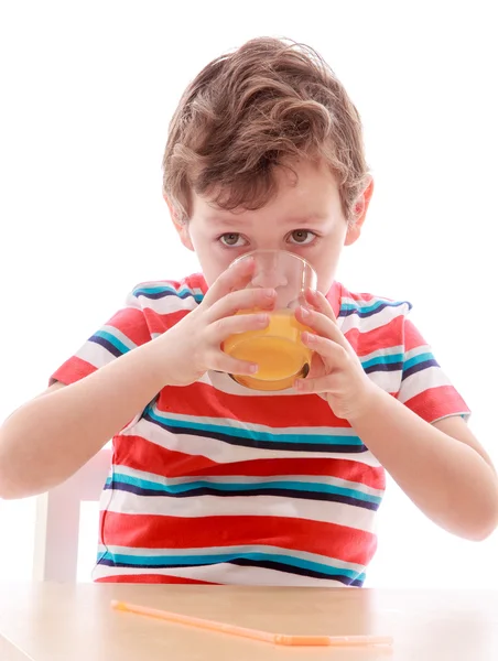 O pequeno rapaz ansiosamente bebendo suco de um copo, close-up — Fotografia de Stock