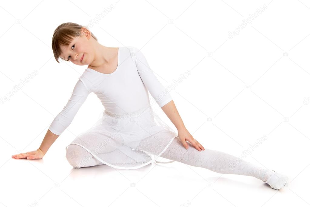 Girl ballerina warming up in a white sports dress