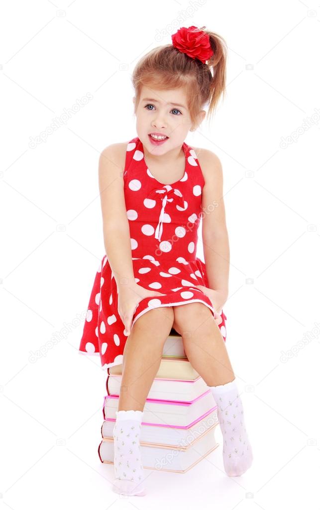  girl in a red dress with polka dots sitting on the books