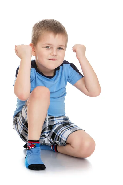Серьезный маленький мальчик в шортах и голубой футболке показывает кулаки — стоковое фото