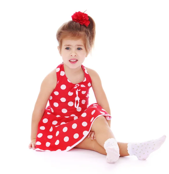 Tender girl in a red polka-dot dress and white socks is sitting — Stok fotoğraf