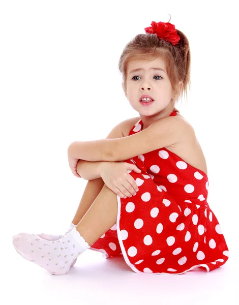 Pretty little girl in a red polka-dot dress and white socks is s — Stok fotoğraf