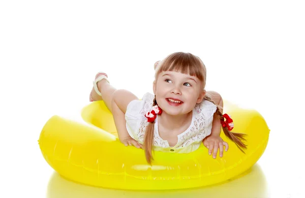 Menina loira alegre feliz com tranças está em um inflável amarelo — Fotografia de Stock