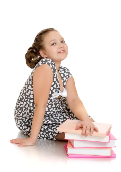 Charming schoolgirl dreaming in a gray dress sitting on the floo — Stockfoto