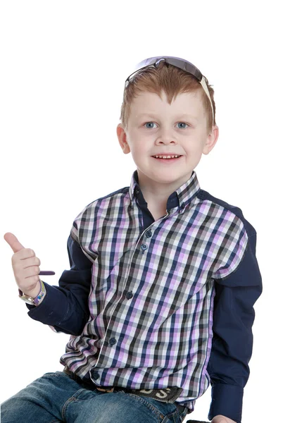 Stylish little blond boy in a plaid shirt and jeans held up the — Stockfoto