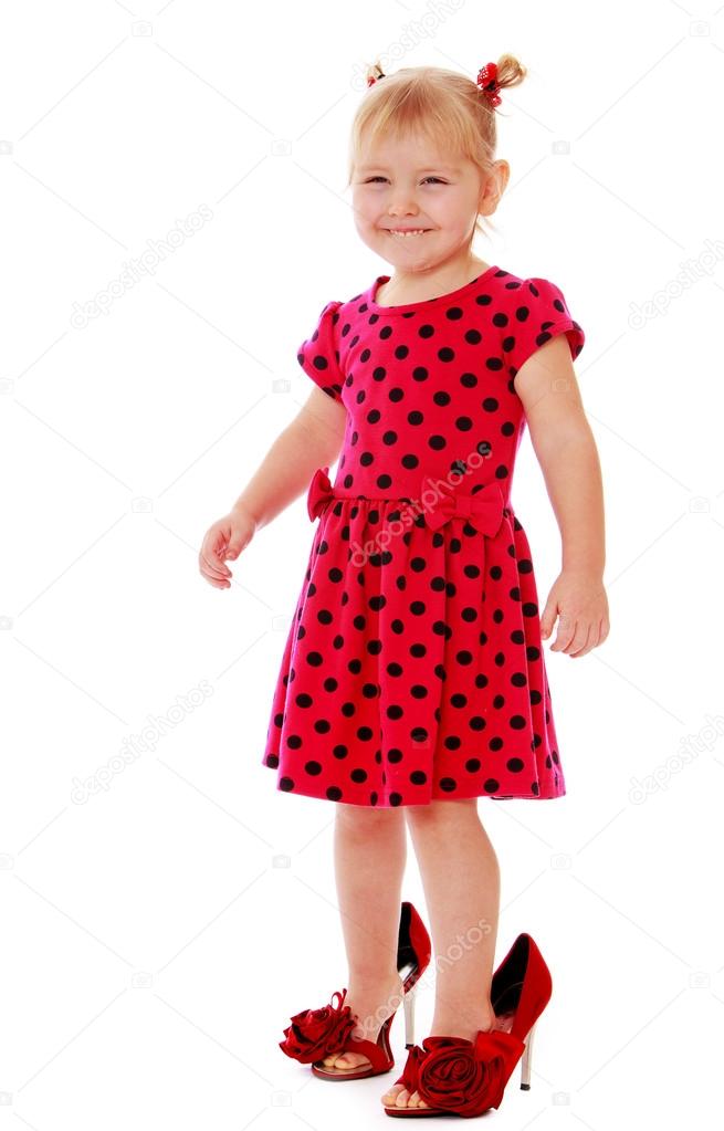 Funny little girl in a red polka dot dress trying on mommys sho Stock ...