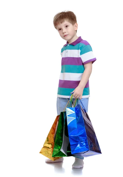 Little boy in striped t-shirt holding bags for shopping — Stock Photo, Image