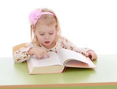 Little girl reading at a table