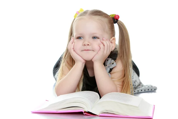 Girl reading a book lying on the floor — ストック写真