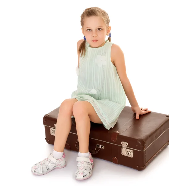 Girl sitting on suitcase — Stock Photo, Image