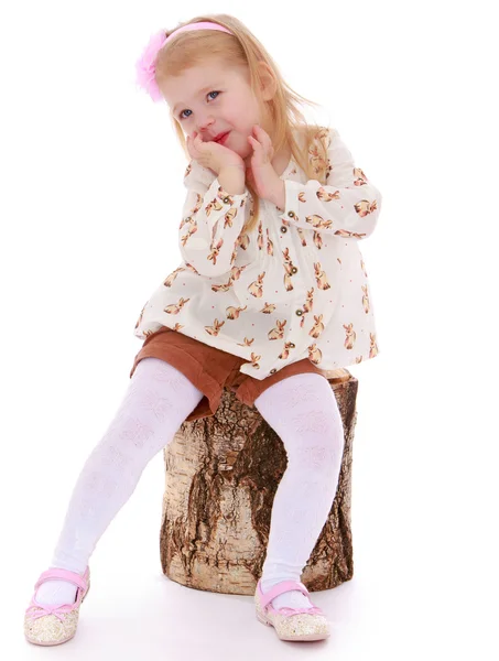 Liten flicka satte sig på en stubbe — Stockfoto