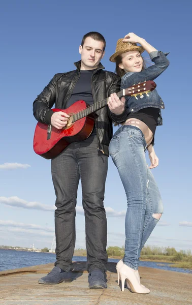 Mladý muž hraje kytara a dívka přidržovala klobouk — Stock fotografie