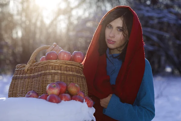Beautiful woman holding a basket with red apples — Stock Photo, Image