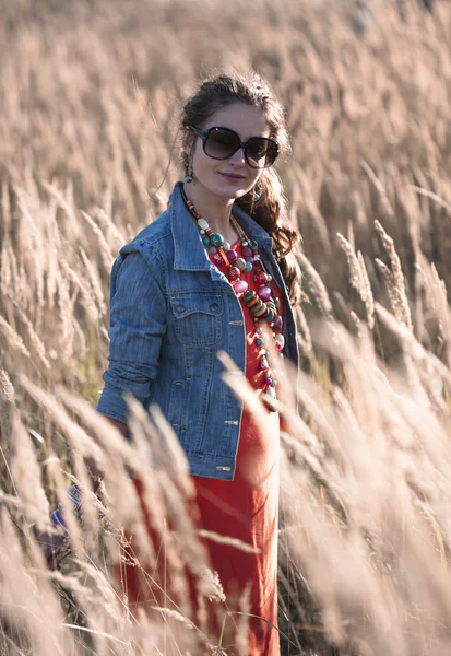 Girl in sunglasses standing on the field in sun rays — Stock Photo, Image