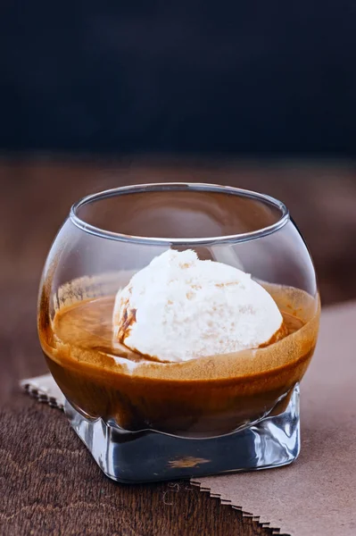 Kahverengi ahşap masa makrosu üzerinde dondurma parçalı bir bardak espresso.