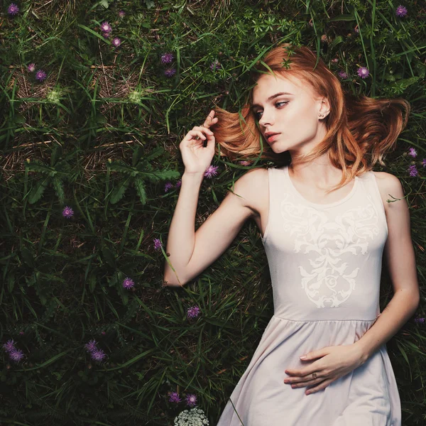 Fabulosa mujer retrato acostado en el campo con flores — Foto de Stock