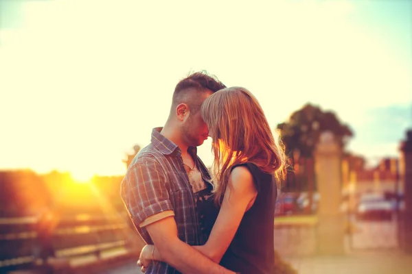 Junges glückliches Paar, das sich am Sonnenuntergang umarmt — Stockfoto