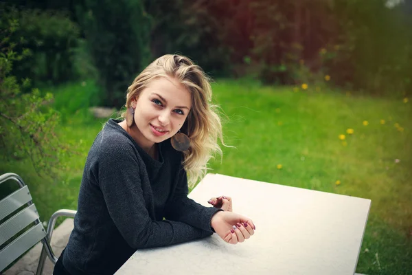 Arka bahçesinde bir masada oturan neşeli kız — Stok fotoğraf