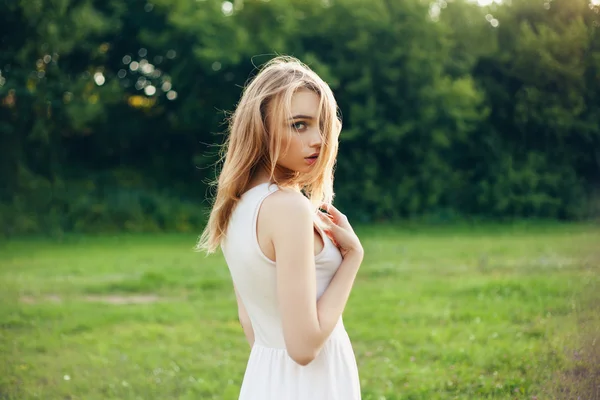 Meisje in het park in een witte jurk op een zonnige dag — Stockfoto