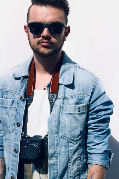Closeup of young hipster man with camera outdoors.