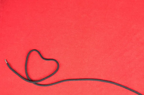 Herzförmiges Schwarzes Seil Auf Rotem Hintergrund — Stockfoto