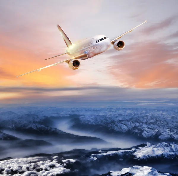 Avião no céu sobre Alpes de inverno no pôr do sol colorido incrível — Fotografia de Stock