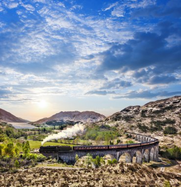 Glenfinnan demiryolu Viyadüğü üzerinde göl günbatımı karşı Jacobite buharlı tren ile İskoçya'da