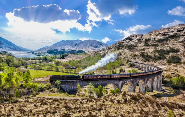 Glenfinnan Ferrocarril Viaducto en Escocia con el tren de vapor jacobita contra la puesta de sol sobre el lago —  Fotos de Stock