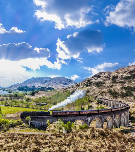 Glenfinnan Ferrocarril Viaducto en Escocia con el tren de vapor jacobita contra la puesta de sol sobre el lago —  Fotos de Stock