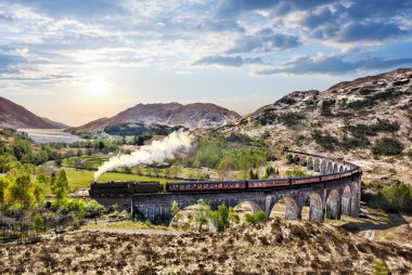 Glenfinnan demiryolu Viyadüğü üzerinde göl günbatımı karşı Jacobite buharlı tren ile İskoçya'da