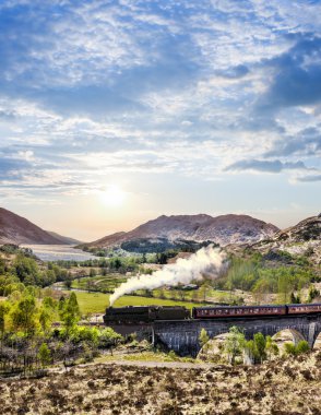 Glenfinnan demiryolu Viyadüğü üzerinde göl günbatımı karşı Jacobite buharlı tren ile İskoçya'da