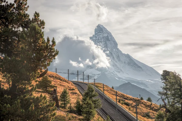 Пик Маттерхорн с железной дорогой против заката в швейцарских Альпах, Швейцария — стоковое фото
