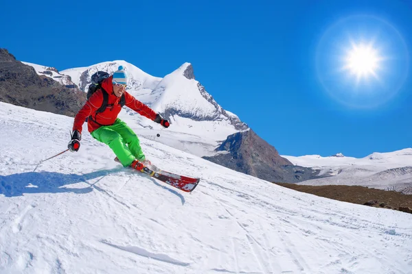 Yokuş aşağı güneş karşı yüksek dağlarda kayak kayakçı — Stok fotoğraf