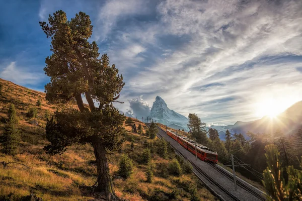 Matterhorn peak med ett tåg mot solnedgången i schweiziska Alperna, Schweiz — Stockfoto