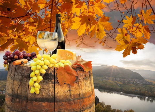 オーストリアのドナウ川に近いスピッツ村に対して樽の上にワインのボトルとワッハウ渓谷の上の秋の夕日 — ストック写真