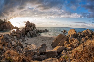 İtalya, Calabria 'da kayaların arasında renkli günbatımına karşı güzel plajlı gök mavisi koy.