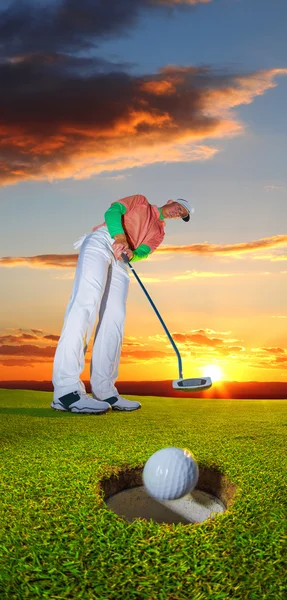 Człowiek, gry w golfa przeciwko kolorowy zachód słońca — Zdjęcie stockowe