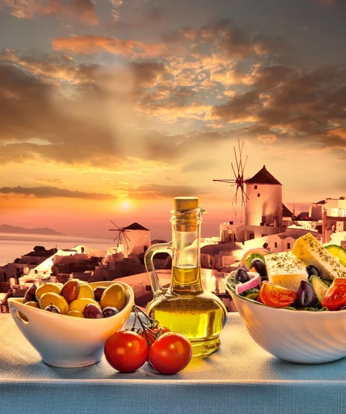 Греческий салат против ветряной мельницы в деревне Ия, остров Санторини в Греции — стоковое фото