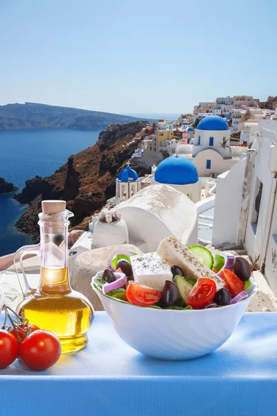 Greek salad against church in Oia village, Santorini island in Greece — Stock Photo, Image